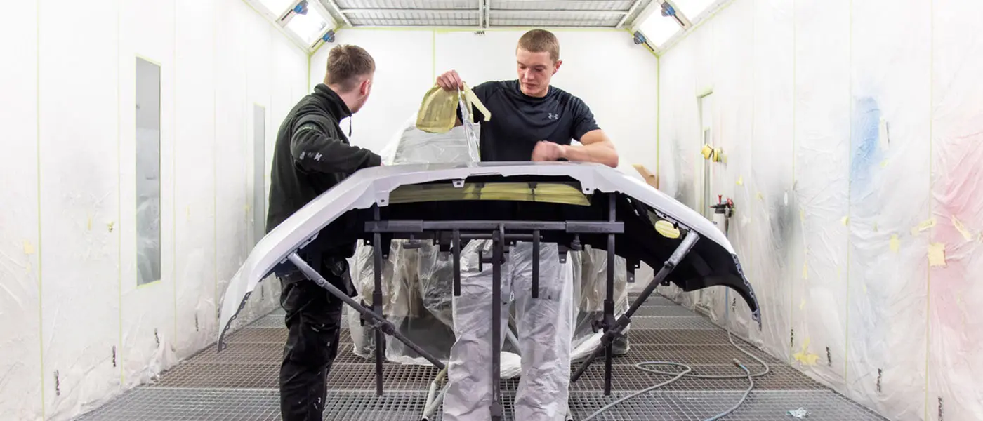 Painters preparing a bumper in the Autocraft paint booth