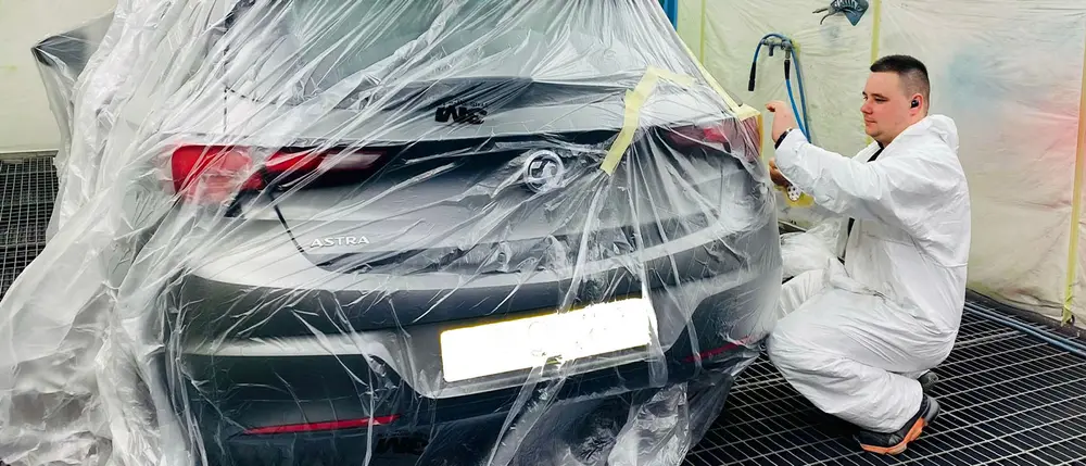 Autocraft painter masking a car before spraying